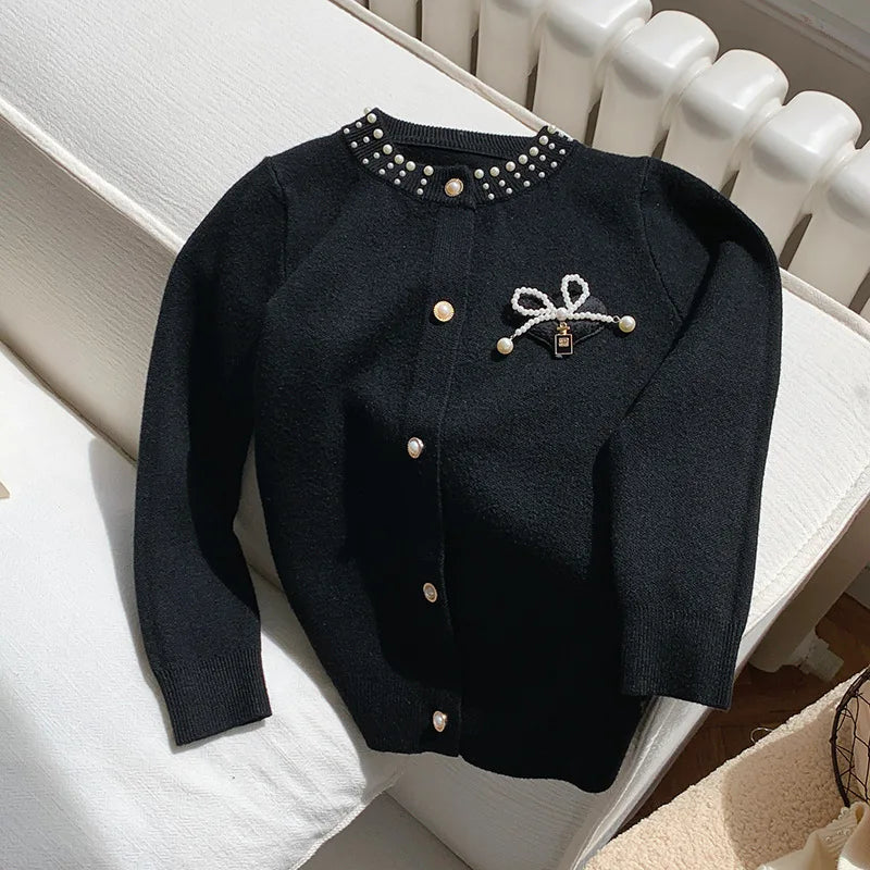 The Chic Black Bows and Pearls Little Girls Cardigan displayed elegantly, accentuated by faux pearls and a bow, perfect for fashionable little girls.