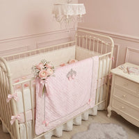Pink raised-dot Minky baby blanket with bows and crystal accents on a white nursery crib.