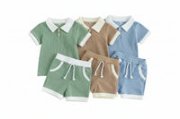 Three children's outfits in green, brown, and blue on a beige background