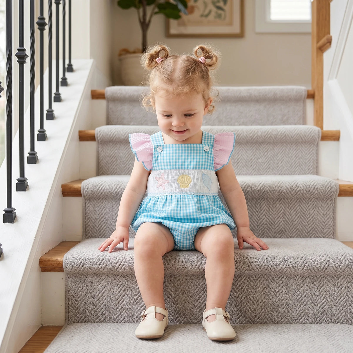 Take Me Out To The Seashore Romper on toddler girl with blue gingham, pink flutter sleeves, sea creature embroidery.