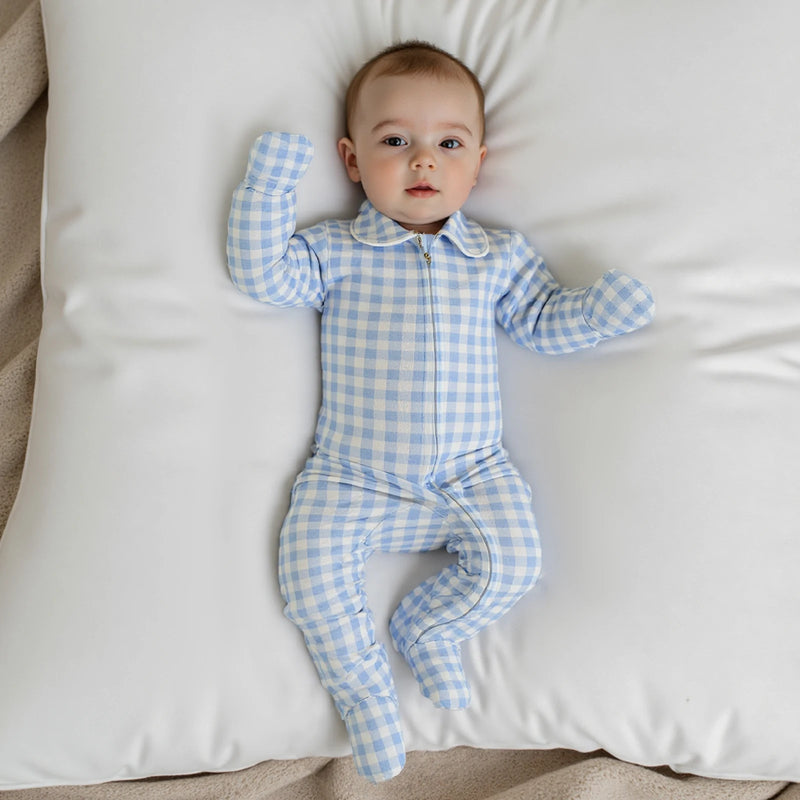Baily Checked Footie in Boca Blue color, featuring a baby lying on a pillow, showcasing the cozy fabric and adorable style.