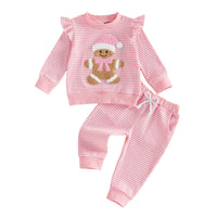 Pink and white striped waffle knit Christmas outfit for girls featuring a gingerbread baby applique, ruffle sleeve pullover, and matching drawstring pants.