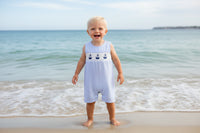 Light blue striped baby romper with sailboat design on a beige background