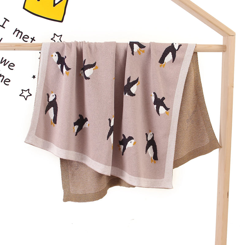 Little Penguins Children's Knit Blanket draped gracefully on a stand, offering a vibrant penguin print that brightens any nursery.