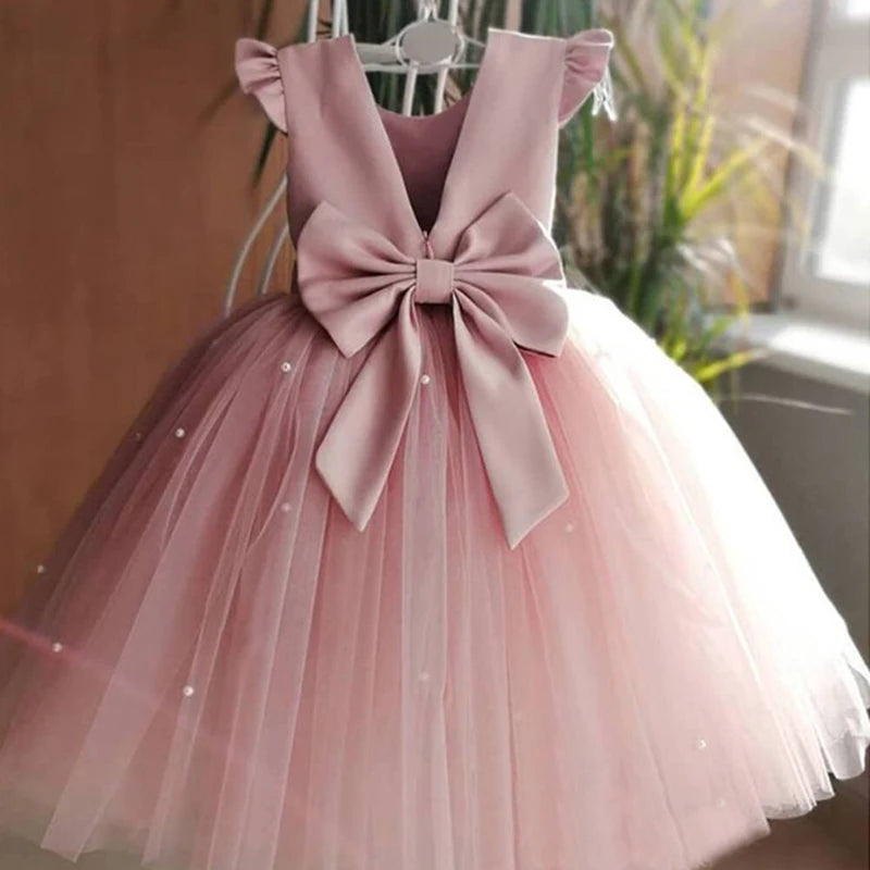 A close-up of a pink 'Chantelle-Elise' V-Back Occasion Dress on a mannequin, featuring a beautiful oversized bow and delicate tulle.