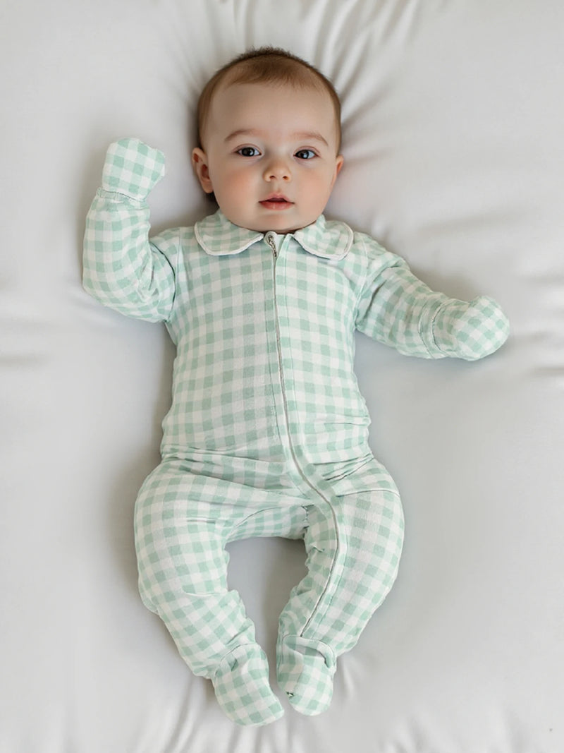 Baby wearing the 'Baily' Checked Footie in Palm Green, showcasing comfort and style in a cozy environment.
