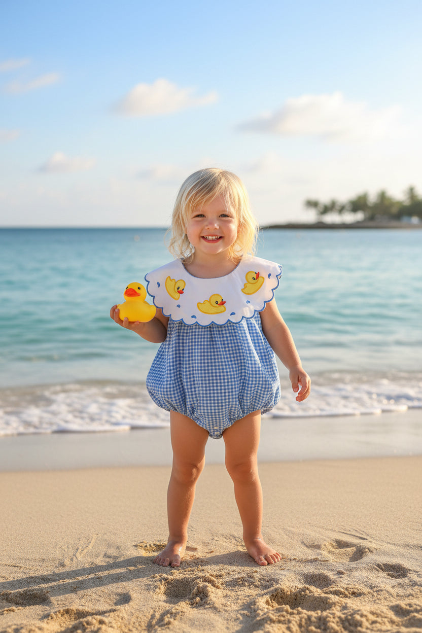 Blue checkered baby romper with duck design on a hanger against a white wall.