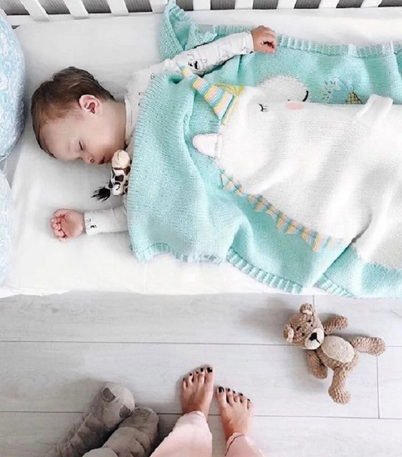A baby's crib featuring a whimsical unicorn blanket, part of the 'Sleepy Tight' cute animal blankets collection.