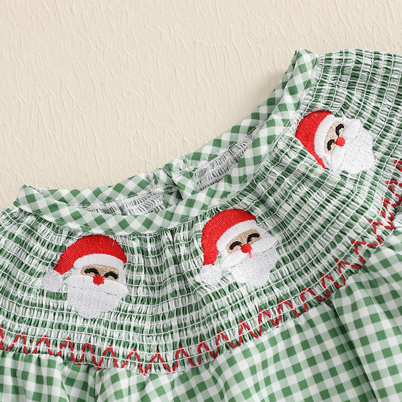 Close-up of Holiday Cuteness Smocked Baby Bubbles showing intricate smocking detail with Santa face embroidery on green gingham fabric.