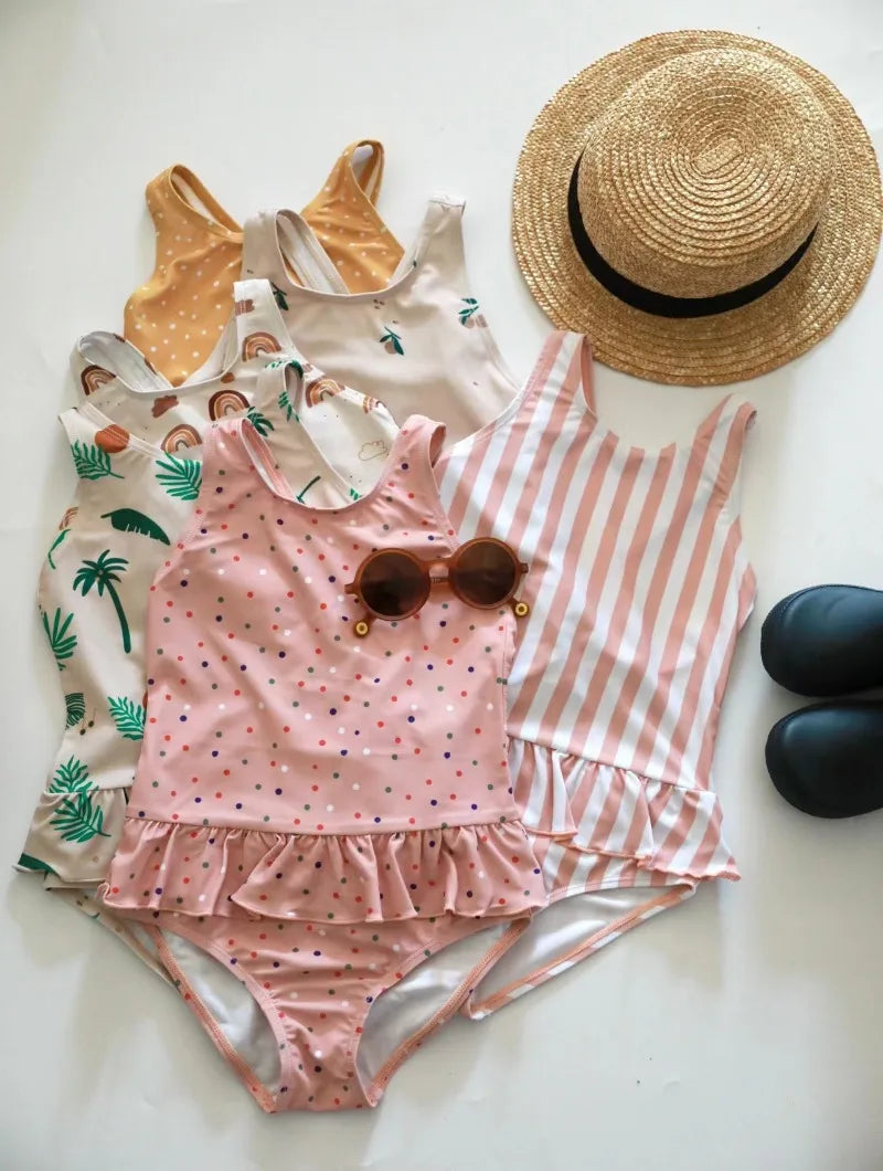 Frilly-print sun-protective one-piece swimsuits for girls ages 1–6 in four prints with crisscross backs.