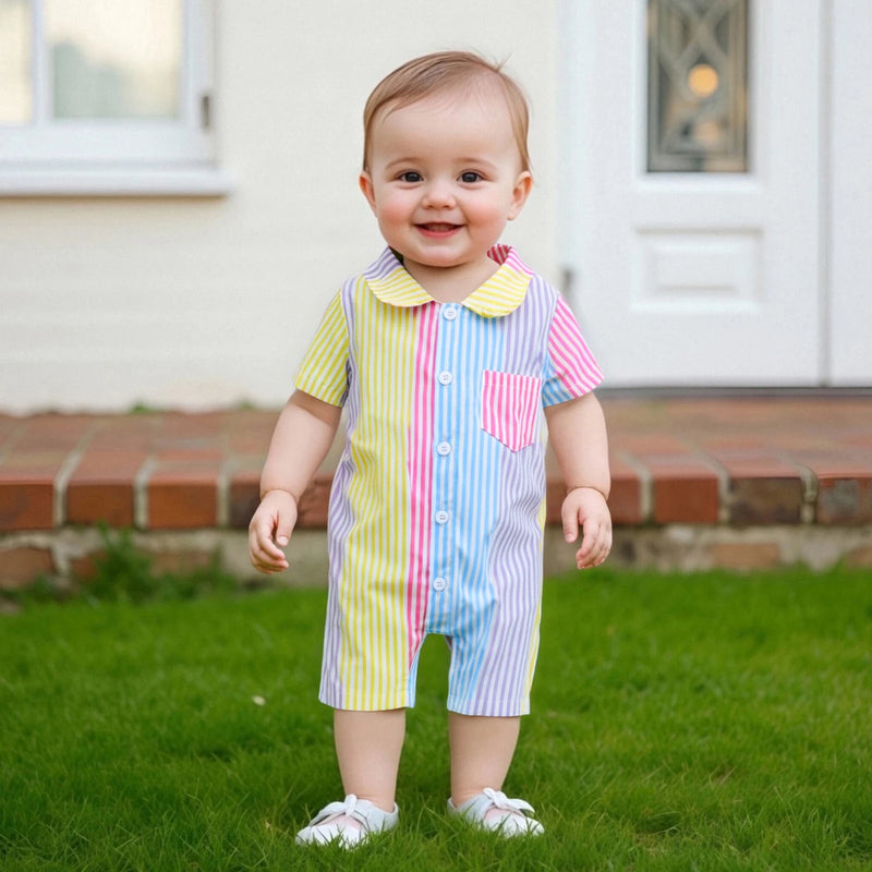Smiling baby in the 'Ryan' Adorable Striped Romper standing on grass, showcasing its playful and vibrant stripe pattern.