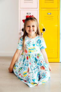 Smiling girl in School Rules Short Sleeve Pocket Twirl Dress with science-themed print beside lockers.