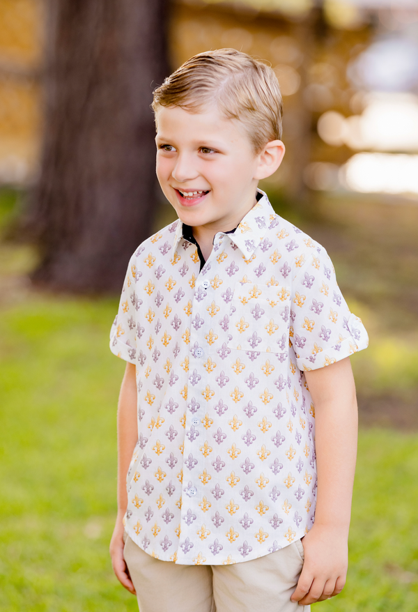 Boy wearing a white short sleeve collared shirt with purple and gold fleur-de-lis print for fans.