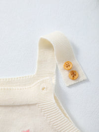 Cream knit romper strap with two amber buttons for babies.