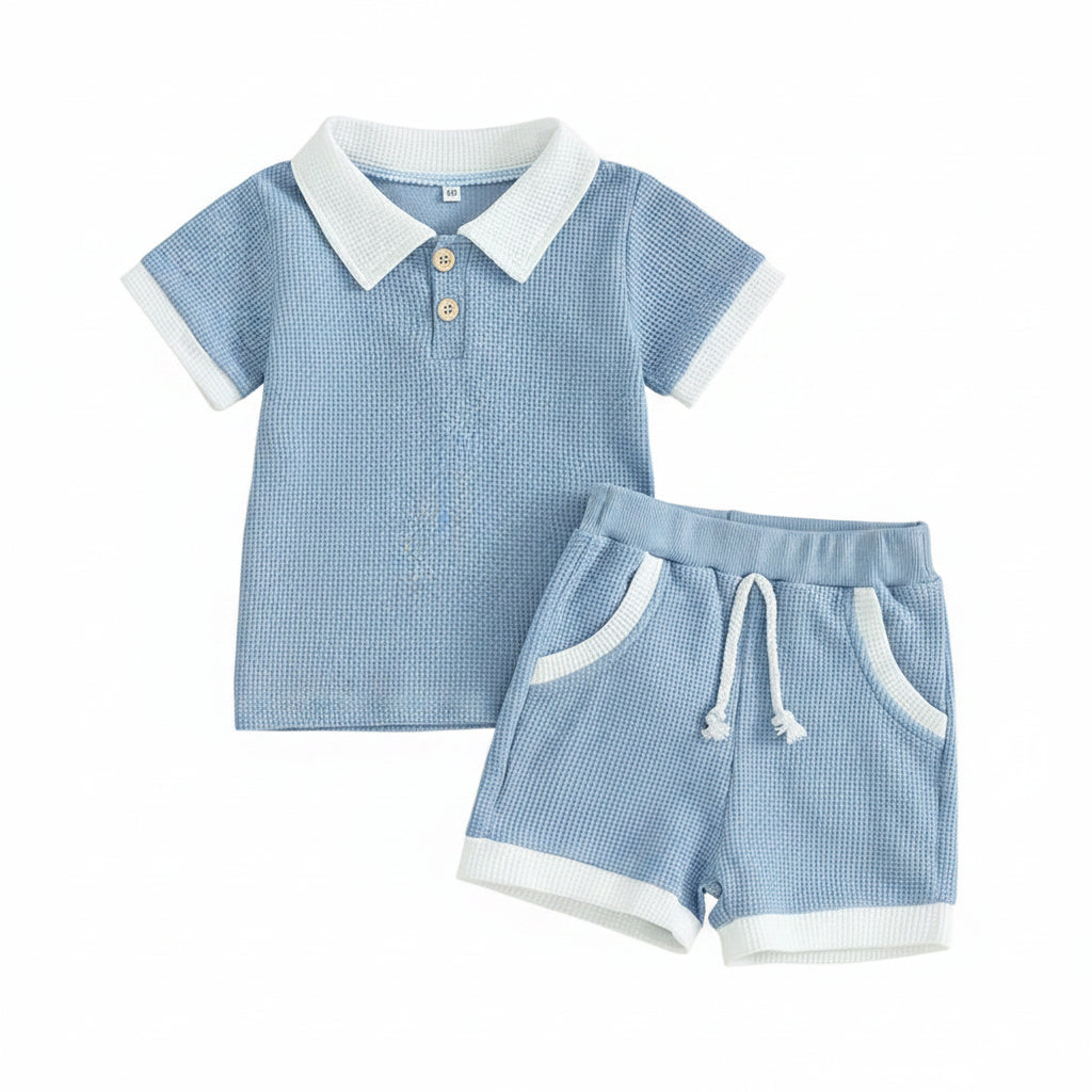 Ocean Breezes boys blue polo-style two-piece shorts set with white collar polo shirt and matching drawstring shorts.