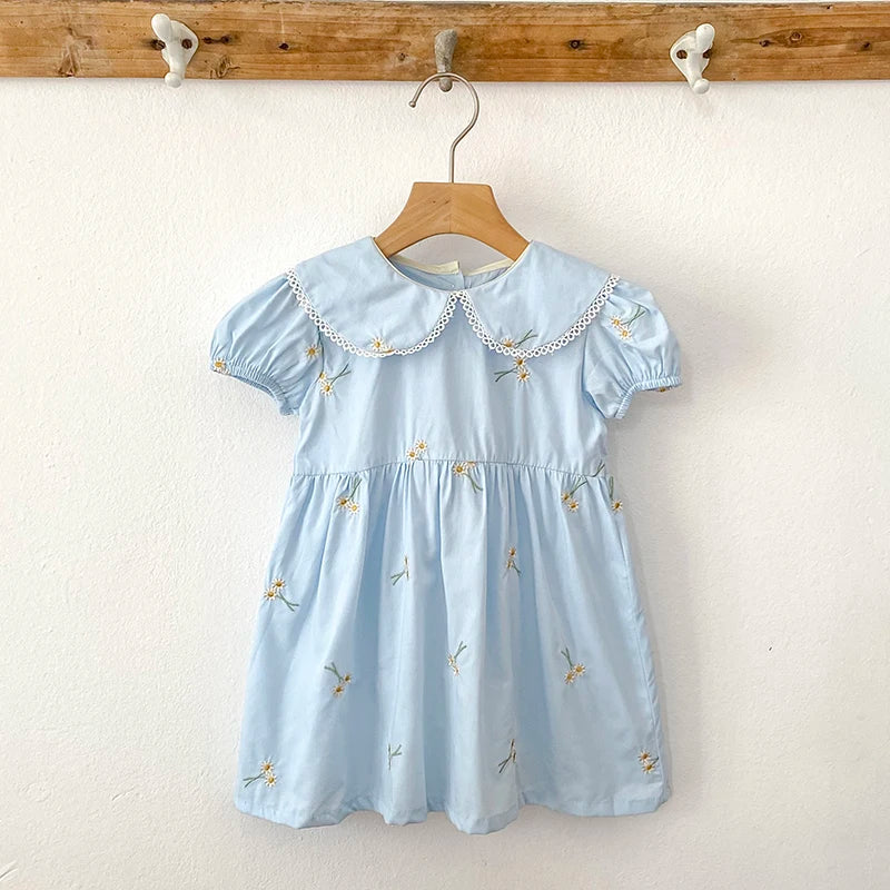 Sweet Lydia Little Girl's Dress in pastel blue adorned with delicate embroidered daisies and a classic collar, ideal for playful moments for ages 2 to 6.