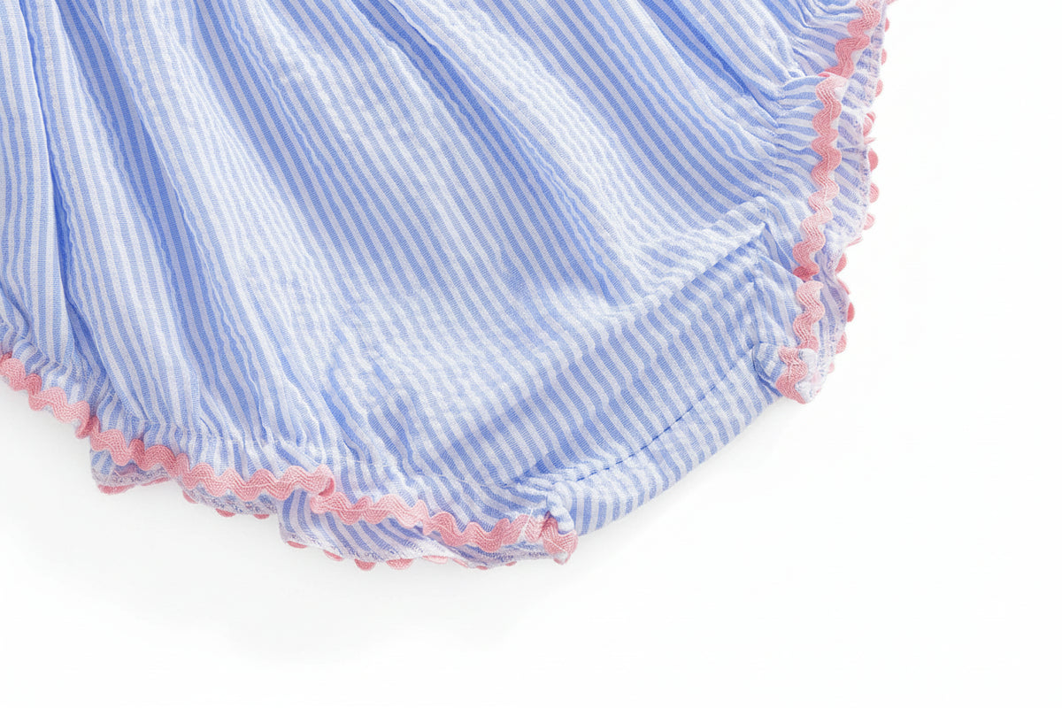 Blue-and-white seersucker fabric close-up with pink scalloped trim along the edge.