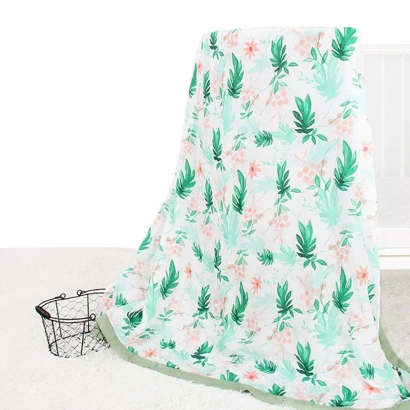 Two-layer bamboo cotton baby swaddle blanket with tropical green leaves and pink flowers on white.