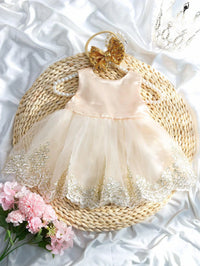 Infant pale-pink satin dress with lace and tulle, gold sequined oversized bow headband and pearl necklace for portraits