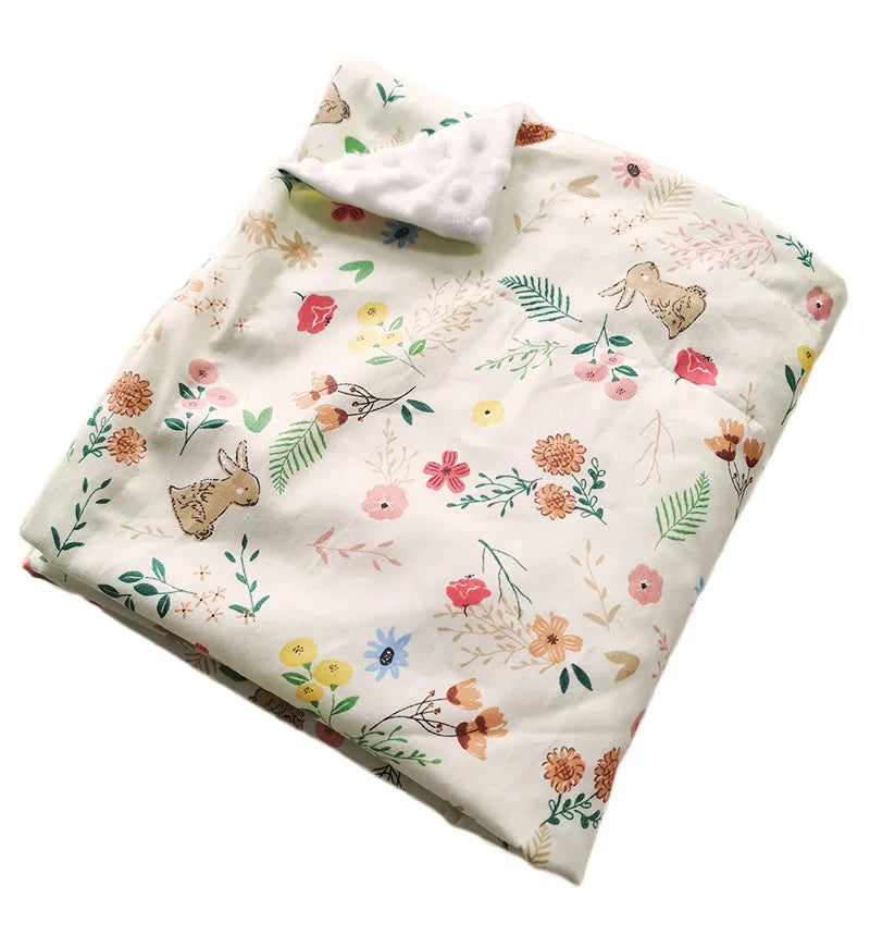Two-sided children's minky blanket with pastel floral prints, bunny motifs, and raised dot texture; soft 100x75 cm.