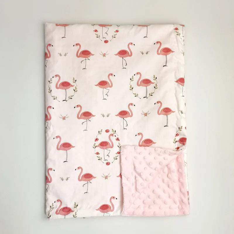 Soft pink minky baby blanket featuring a flamingo print with floral wreaths and a textured dot fleece backing, perfect for toddlers.