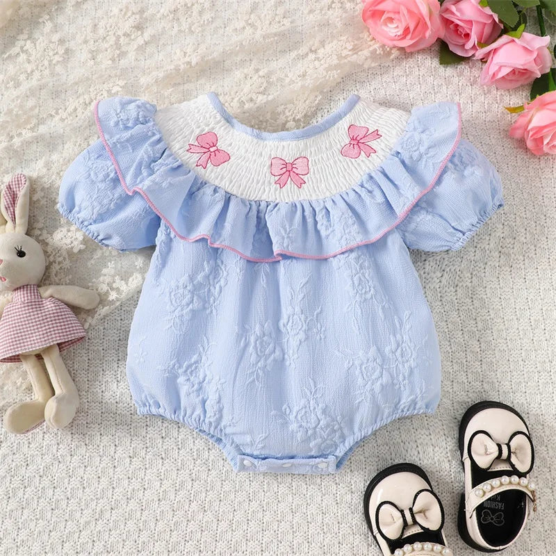 Three Little Bows & Frills Smocked Baby Dress displayed with a soft blue color, featuring a smocked neckline adorned with three pink bows, perfect for baby girls.