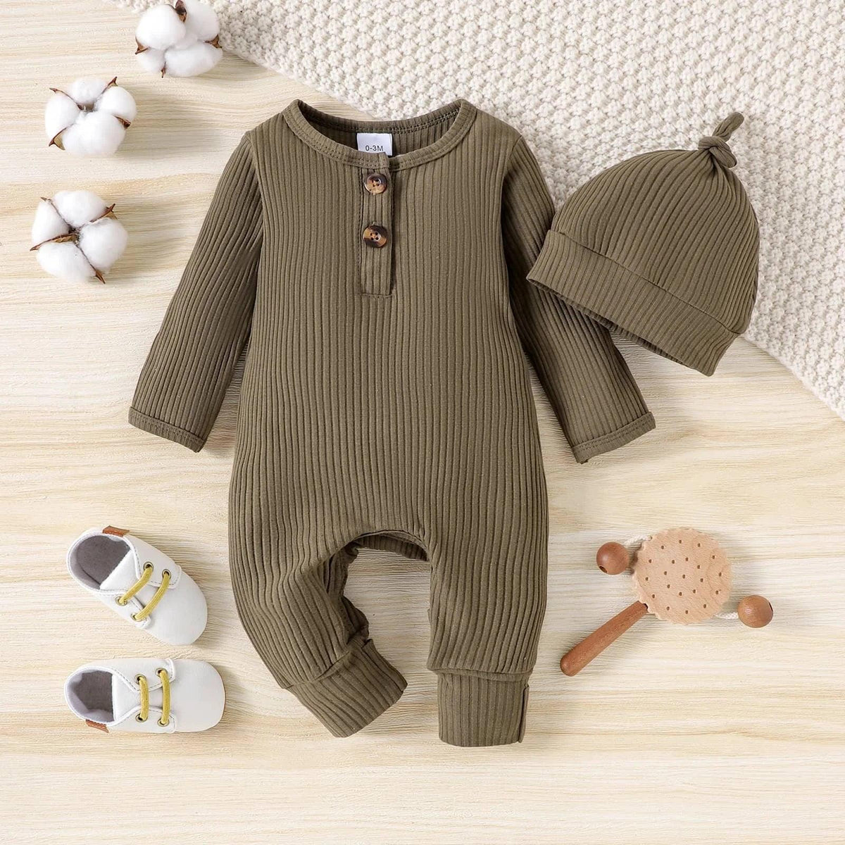 olive green ribbed romper for baby with matching hat laid flat with white baby shoes and wooden rattle