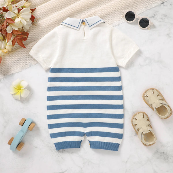 Baby romper with blue and white stripes on a light surface with toys and flowers.