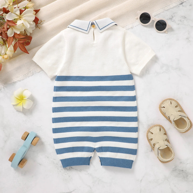 Baby romper with blue and white stripes on a light surface with toys and flowers.