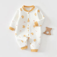 White quilted baby romper with yellow bear prints and trim, long sleeve cozy warmth, unisex cotton exterior with wooden bear teether nearby.