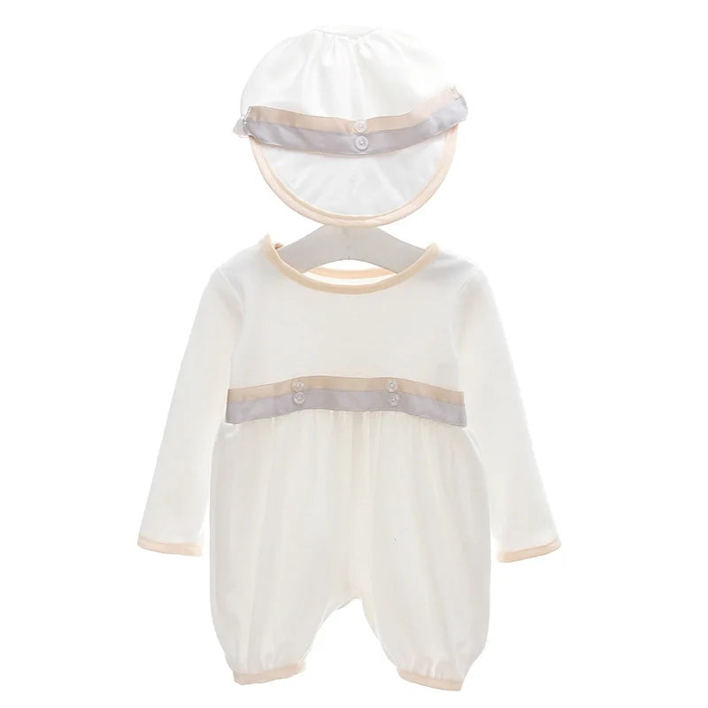 White formal baby boy romper set with matching hat. Features beige trim, decorative buttons, and long sleeves for special occasions.