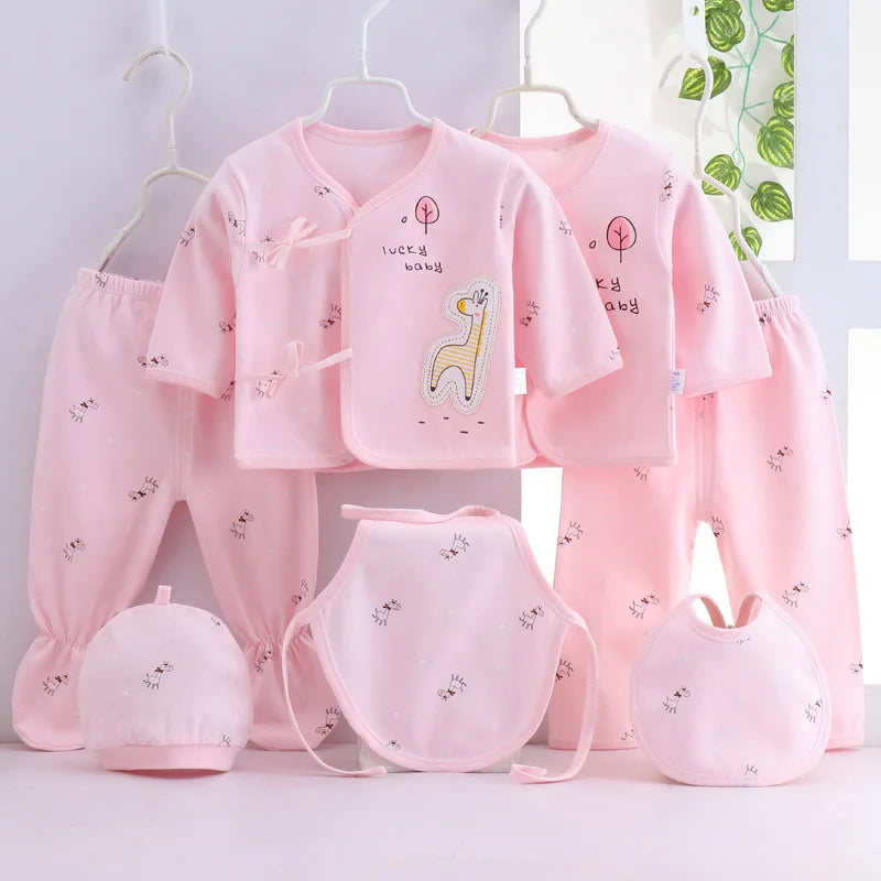 Playful giraffe-themed 7-piece pink newborn layette set with two tops, two pants, two bibs, and hats.