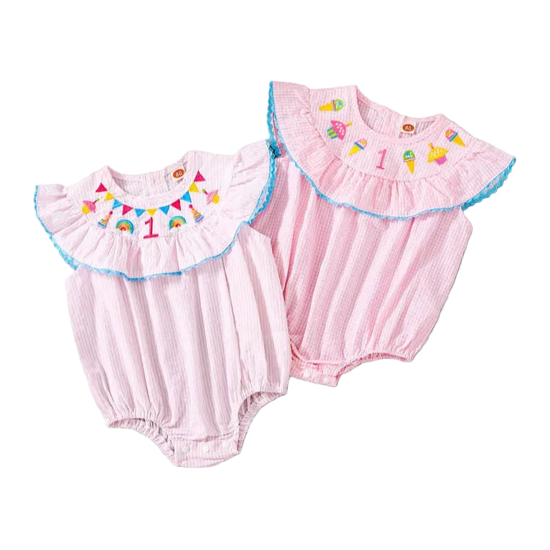 Two pink seersucker birthday girl bubble rompers with Atlantic blue trim, ruffled collars, sleeves, snaps at the legs.