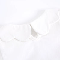 Close-up of a white garment featuring a wide, scalloped Peter Pan collar.