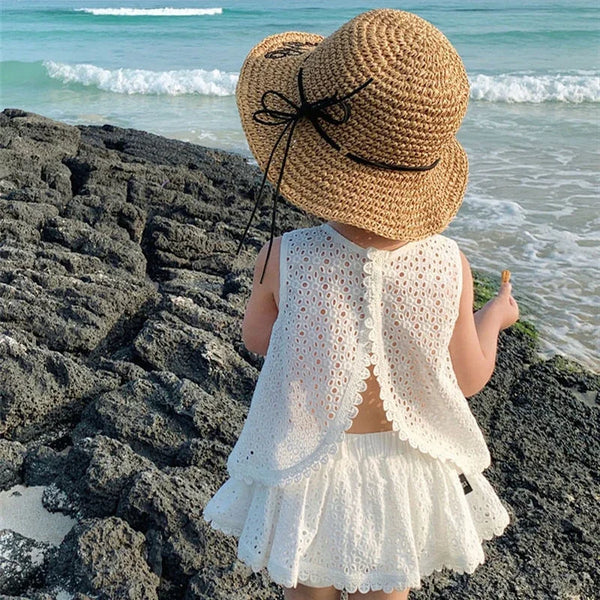 Little girl wearing Wentworth white Summer and Lace 2 Piece Skort and Top Set on the beach with a straw hat.