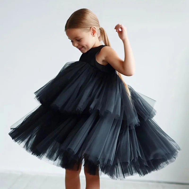 Girl wearing Cara Ann tiered tulle party dress in black, round neckline, mid-calf length.