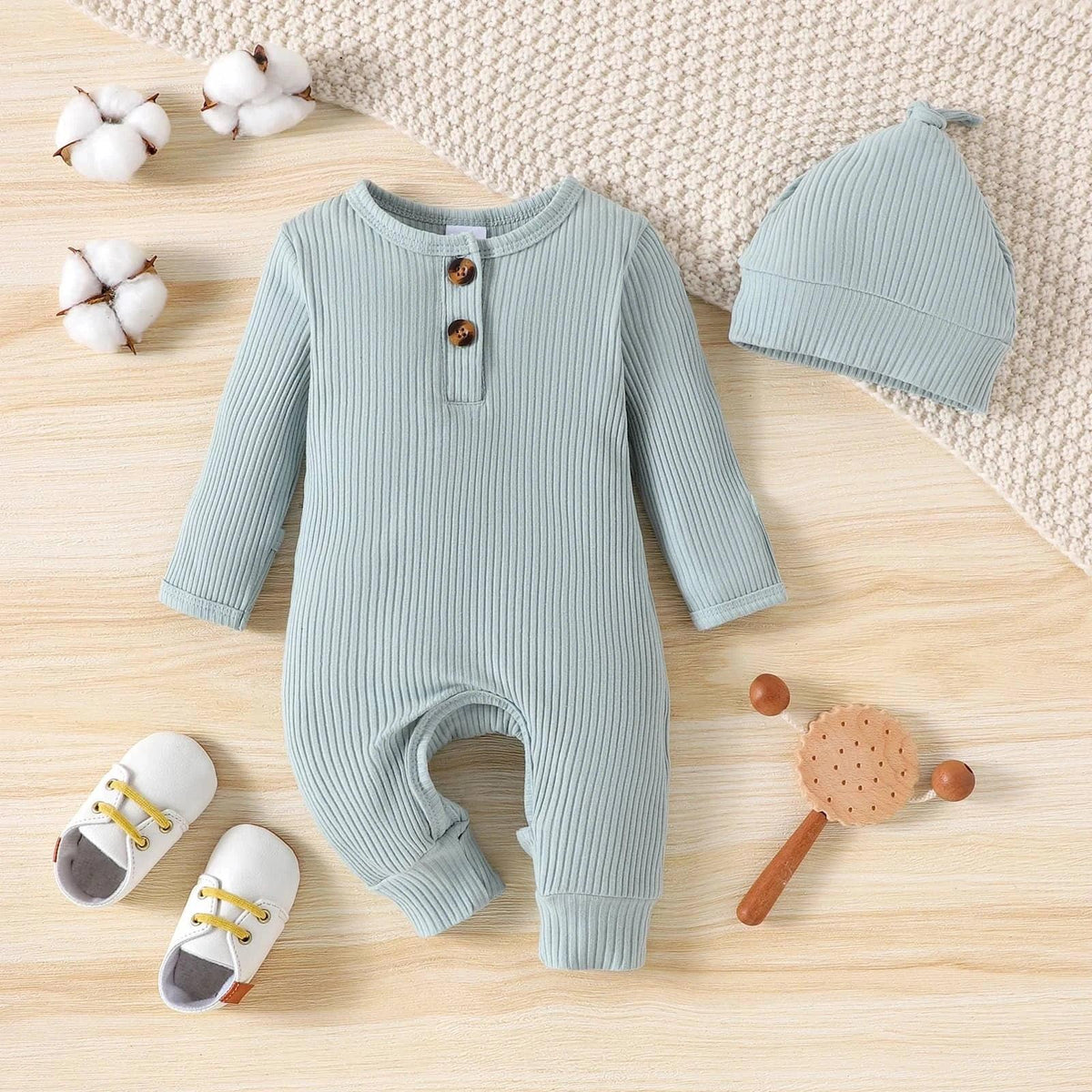 light blue ribbed romper with matching hat for baby laid flat with shoes and toys