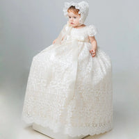 Toddler in ivory full-length lace gown with satin bow and matching bonnet for baptism, christening, or wedding portraits.