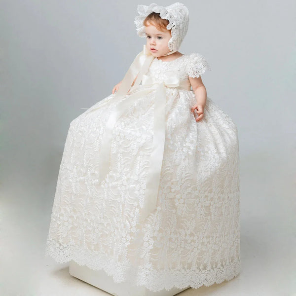 Toddler in ivory full-length lace gown with satin bow and matching bonnet for baptism, christening, or wedding portraits.