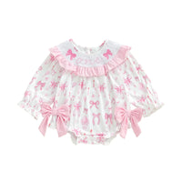 Baby romper with pink bows and ruffles on a white background