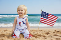 Child wearing a patriotic outfit with 'USA' on a wooden step.