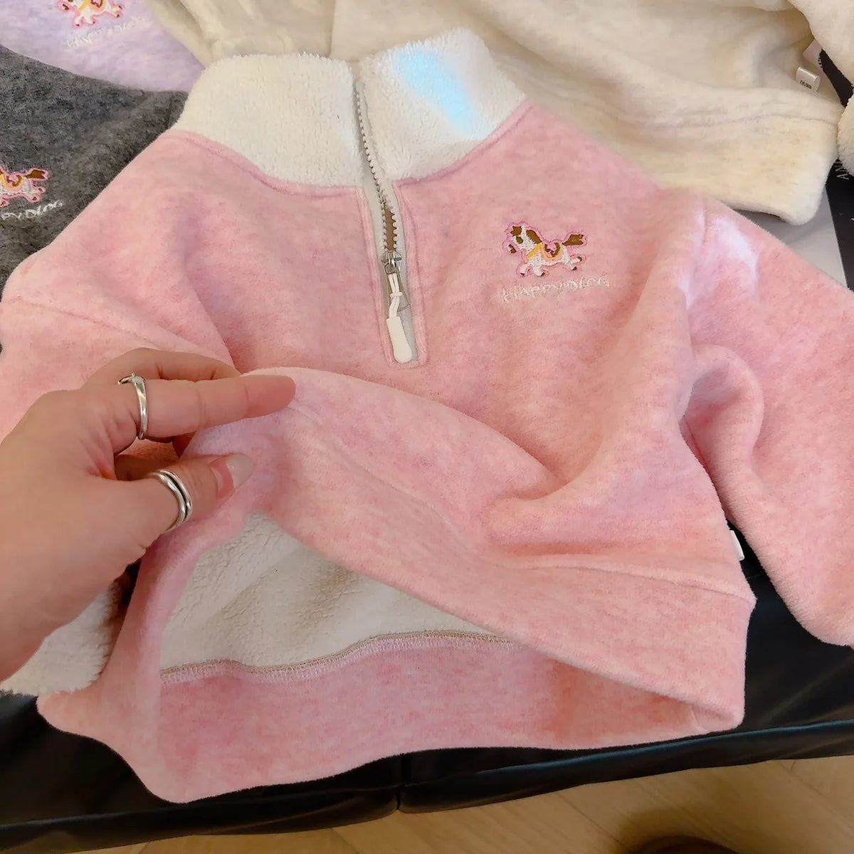 Pink kids fleece half-zip pullover with embroidered horse detail and soft white sherpa lining for cozy autumn and winter wear.