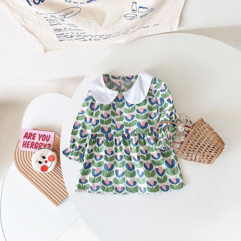 A view of the "Mariella" Floral Print Peter Pan Collar Dress on a table, showcasing the green floral design and classic collar.