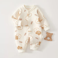 Cream quilted baby romper with cute bear prints and long sleeves, shown with a wooden bear teether for cozy warmth.