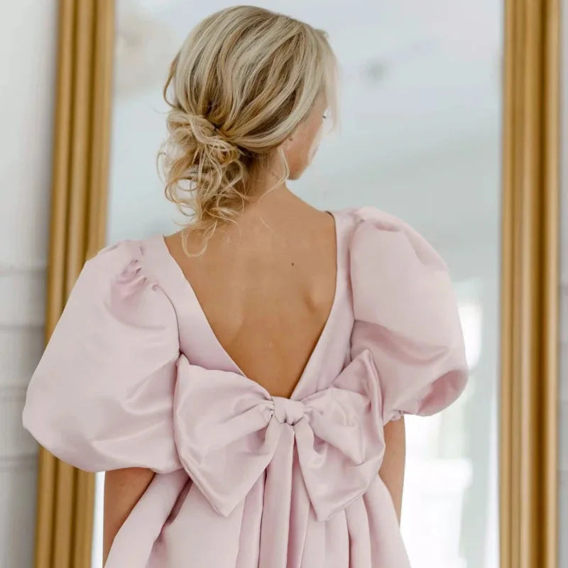 Back detail of the 'Arora' Puffed Sleeved Party Dress featuring an oversized bow and v-back design, perfect for elegant occasions.