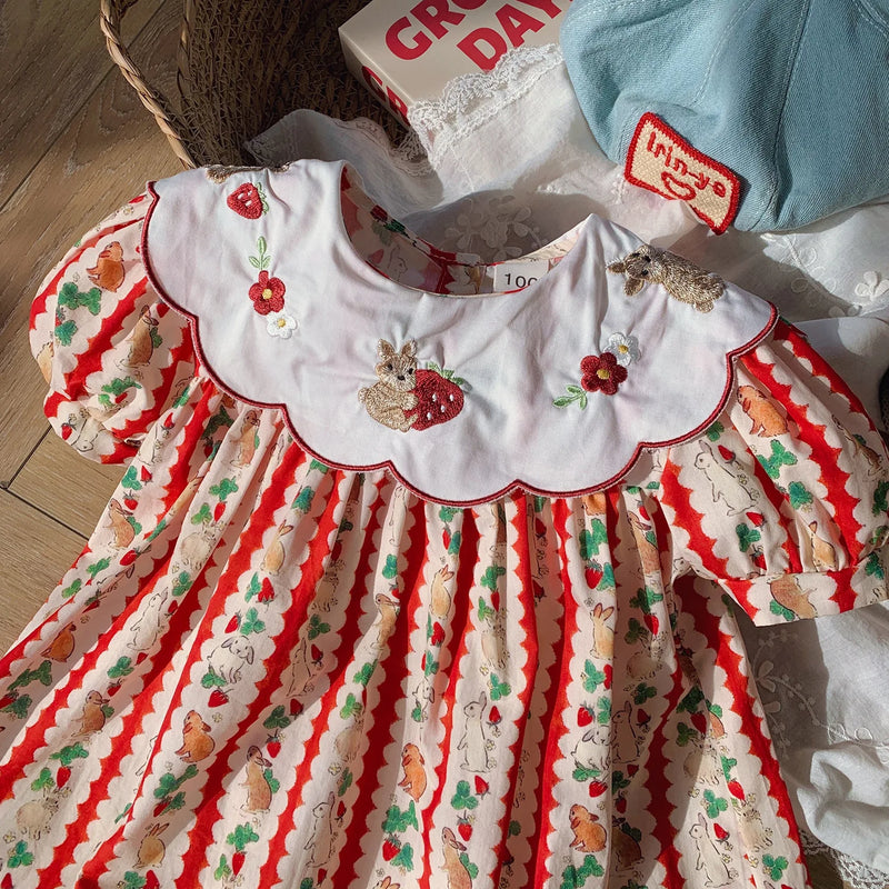 Close-up of the embroidered details on the 'Constance-Marie' classic embroidered dress for girls, showcasing colorful strawberry prints and a scalloped Peter Pan collar.