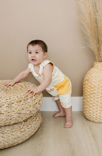 Baby wearing GOTS certified organic cotton sleeveless romper with smiley bolts print and yellow pocket.