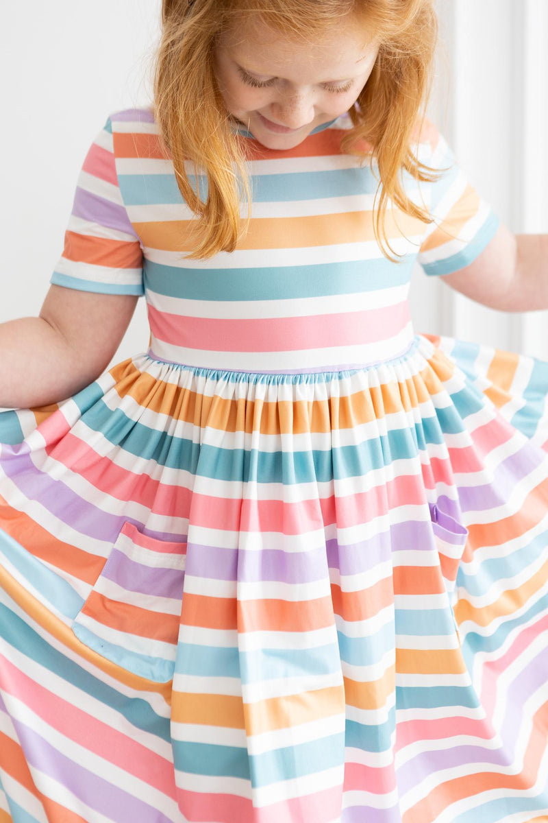 Close-up of a girl in a Spring Stripes Short Sleeve Pocket Twirl Dress for Girls, highlighting the playful twirly skirt and fun pockets, designed as a perfect twirl dress for girls.
