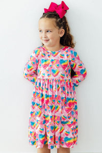 Girl wearing Sugar & Spice 3/4 Sleeve Pocket Twirl Dress with rainbow hearts on pink, full twirl skirt