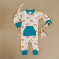 Sunrise organic cotton playsuit with sun pattern, teal pocket and cuffs, lay flat with wooden teether.